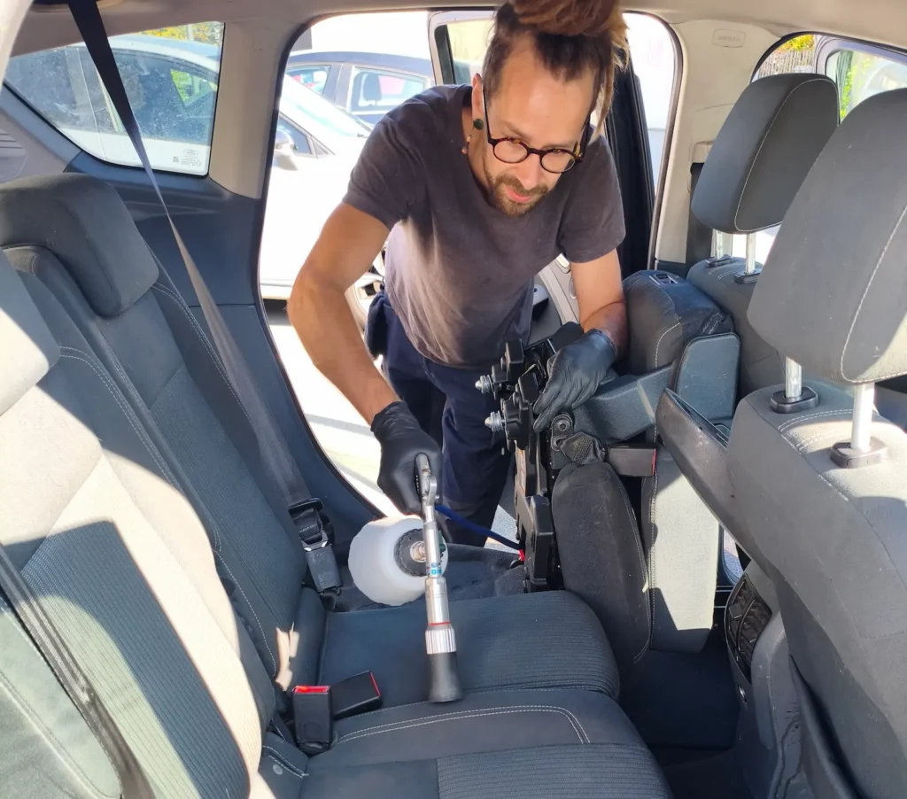 Professionnel en train de réaliser un nettoyage intérieur de voiture à domicile
